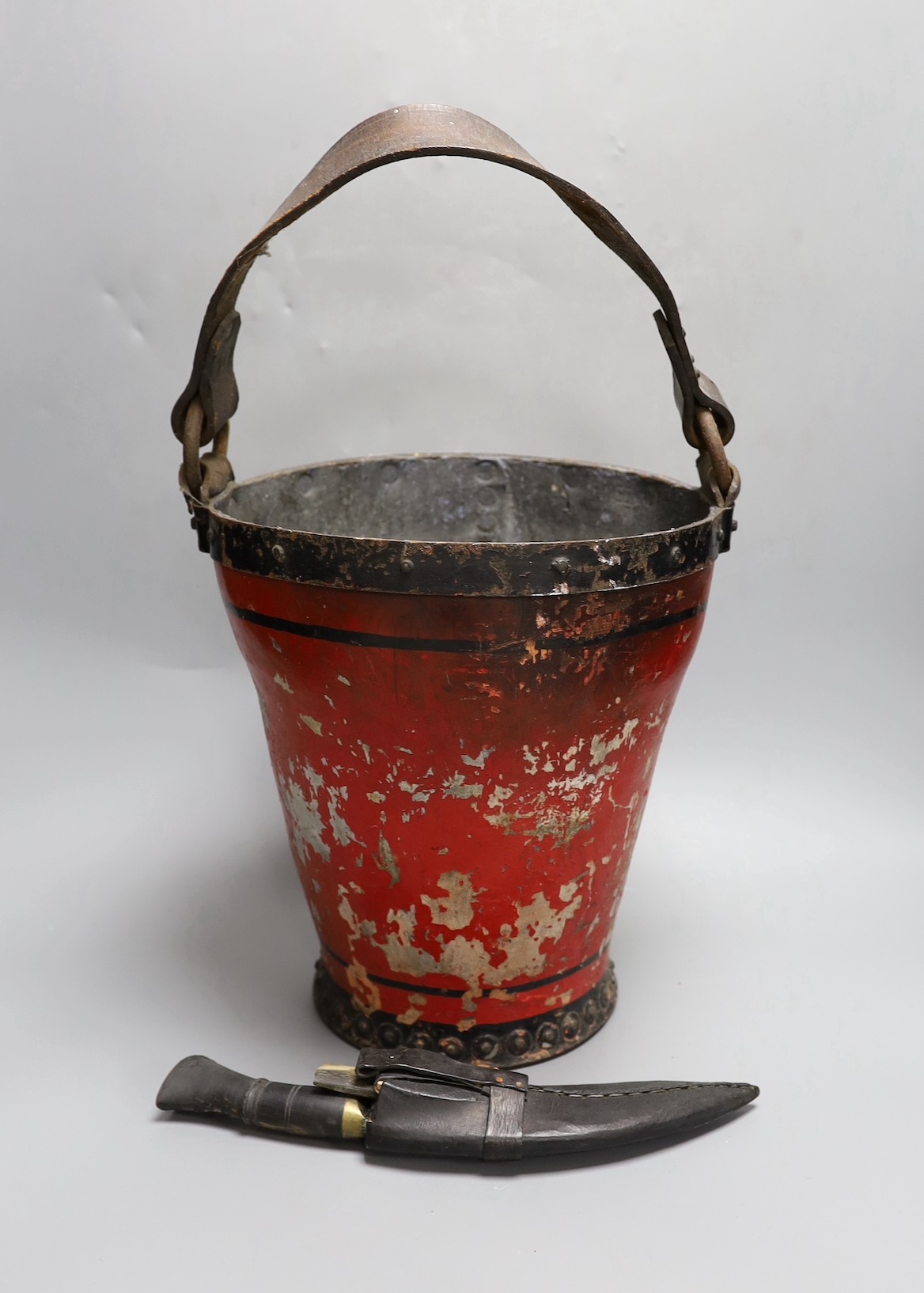 A 19th century iron bound painted leather fire bucket together with a small kukri knife